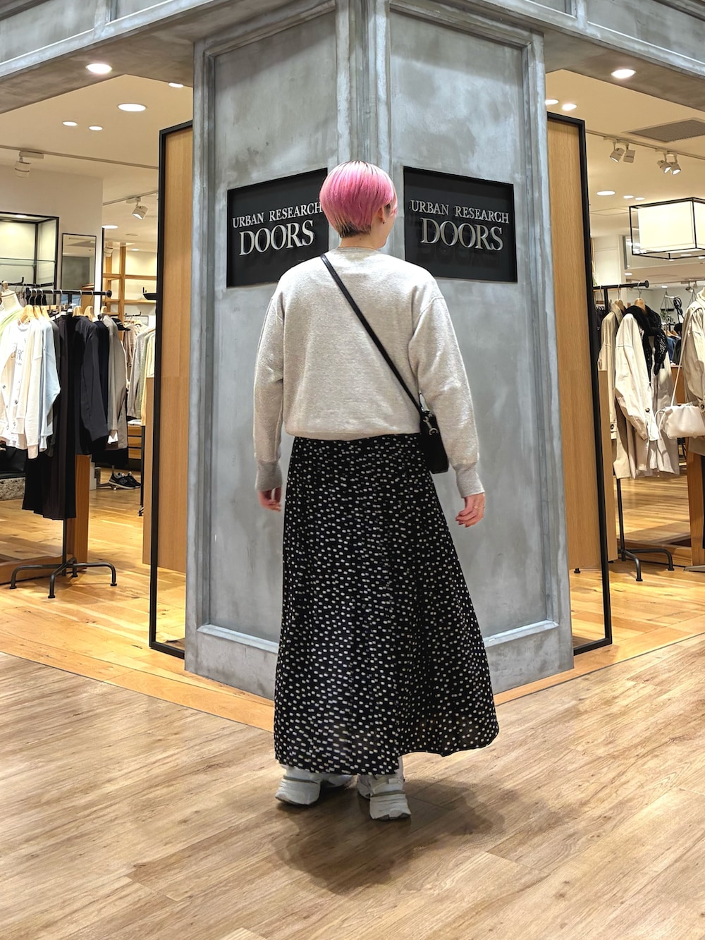 シルバー系のスニーカー、ベージュ系のスウェット、ブラック系のスカートを着用したレディースの春コーディネートの3枚目の写真