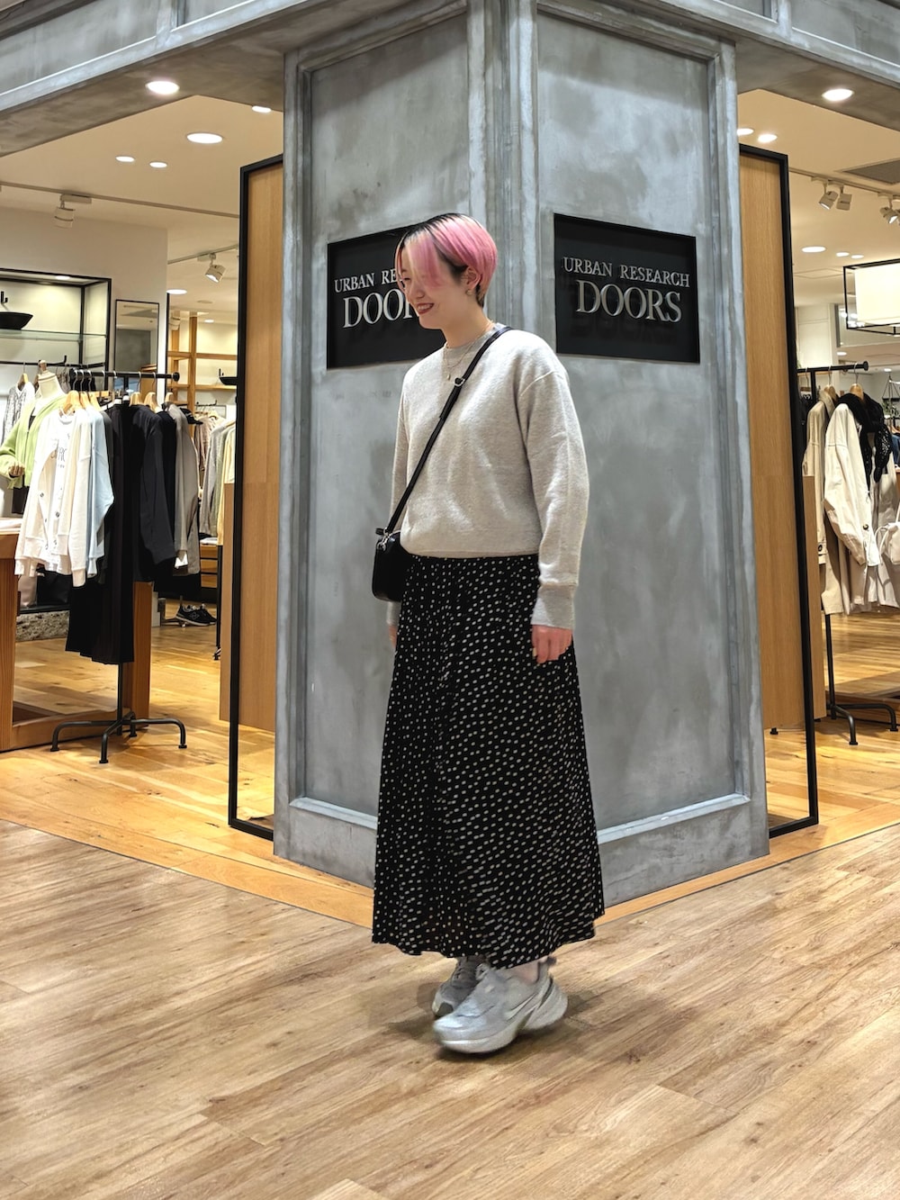 シルバー系のスニーカー、ベージュ系のスウェット、ブラック系のスカートを着用したレディースの春コーディネートの2枚目の写真
