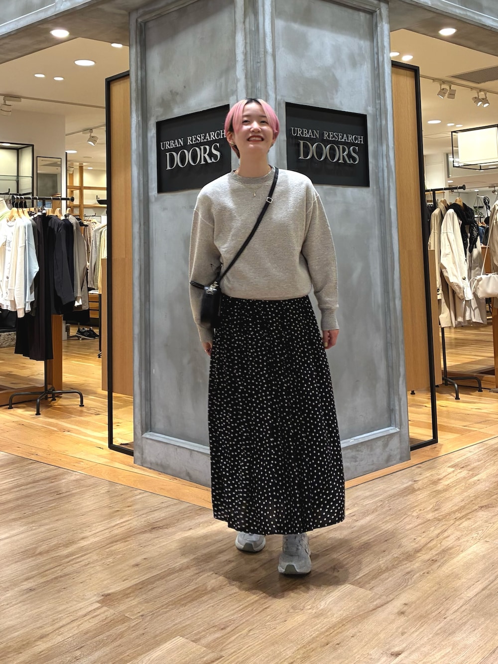 シルバー系のスニーカー、ベージュ系のスウェット、ブラック系のスカートを着用したレディースの春コーディネートの7枚目の写真