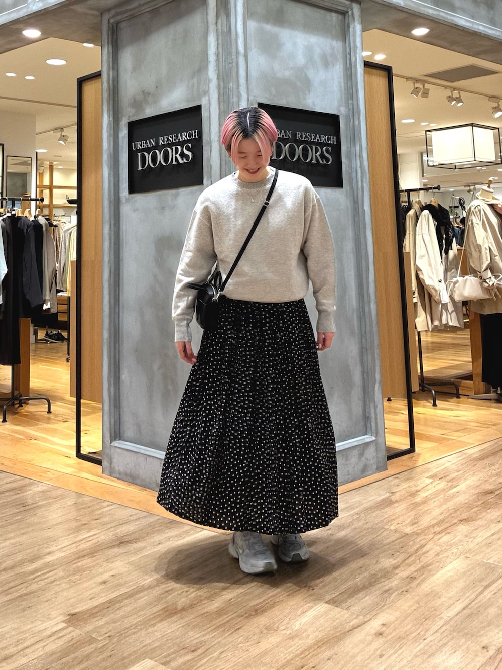 シルバー系のスニーカー、ベージュ系のスウェット、ブラック系のスカートを着用したレディースの春コーディネートの6枚目の写真