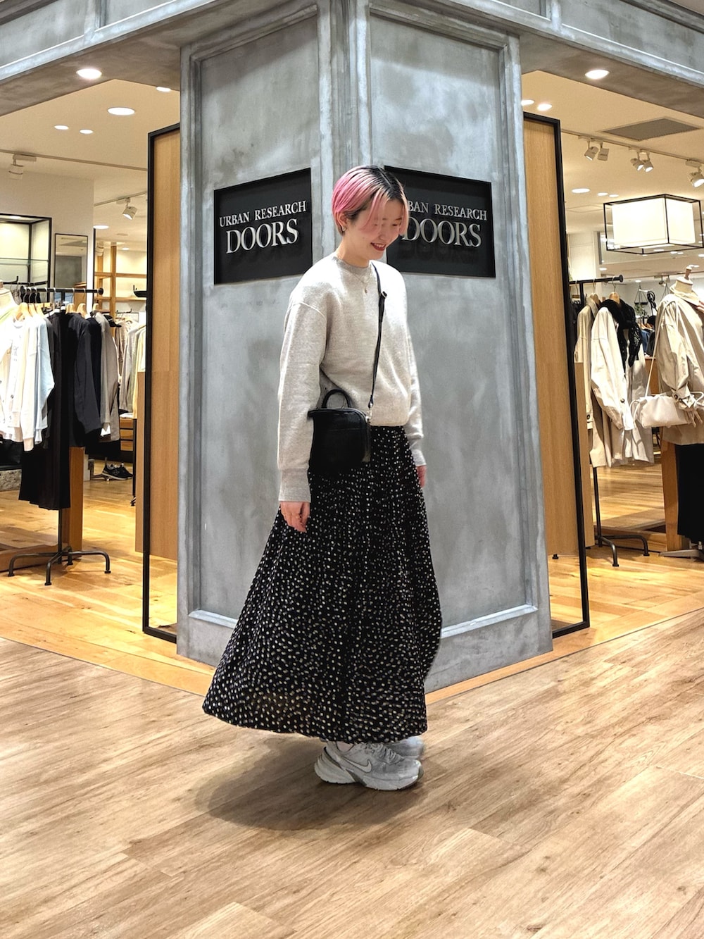 シルバー系のスニーカー、ベージュ系のスウェット、ブラック系のスカートを着用したレディースの春コーディネートの5枚目の写真