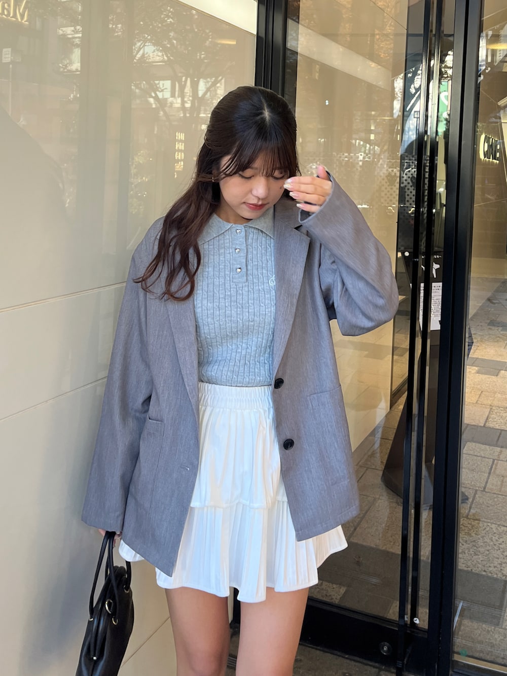 グレー系のテーラードジャケット、ブルー系のニット/セーター、ホワイト系のスカートを着用したレディースの冬コーディネートの2枚目の写真