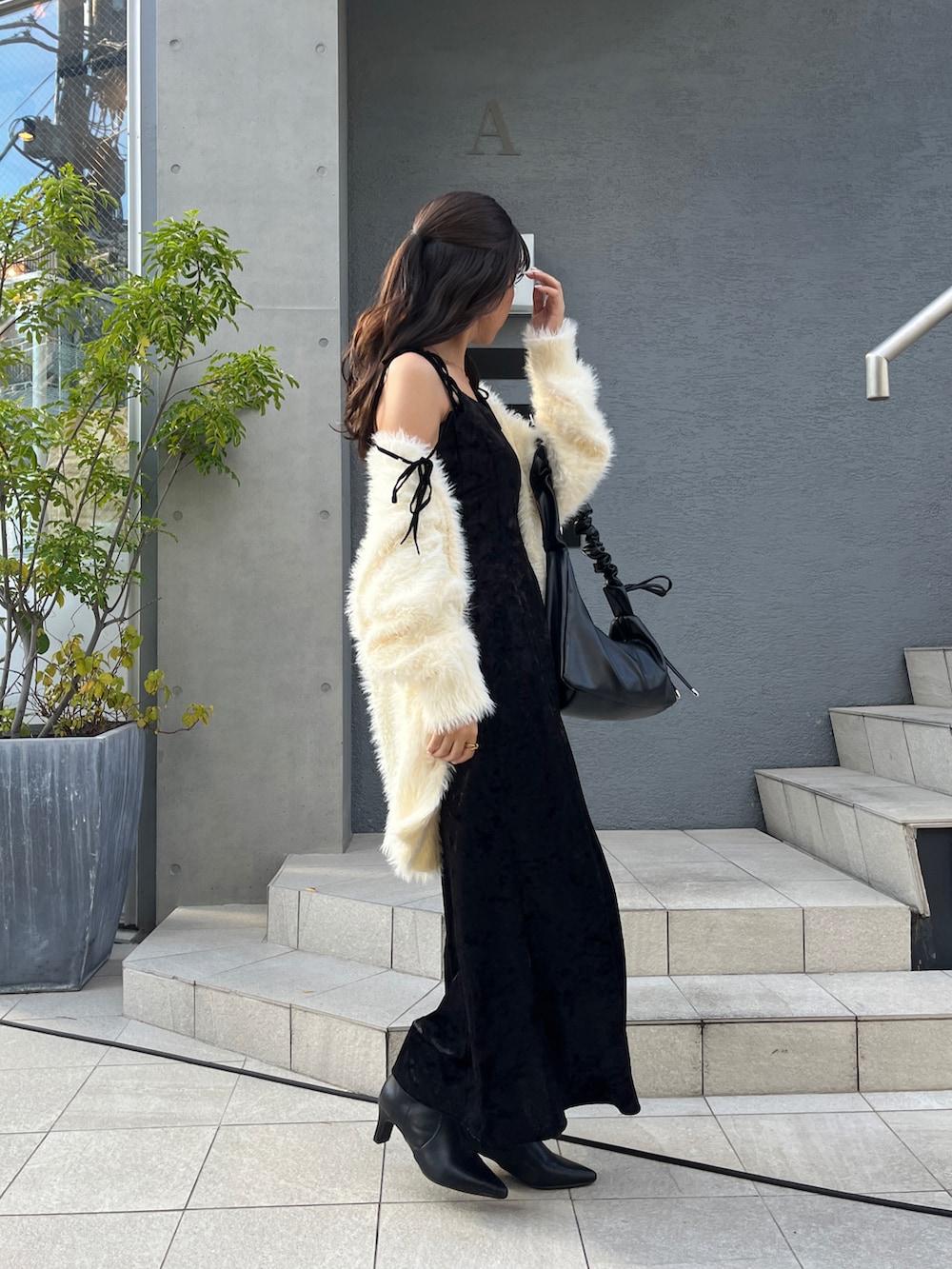 ホワイト系のカーディガン/ボレロ、ブラック系のワンピース、ブラック系のブーツを着用したレディースの秋コーディネートの3枚目の写真