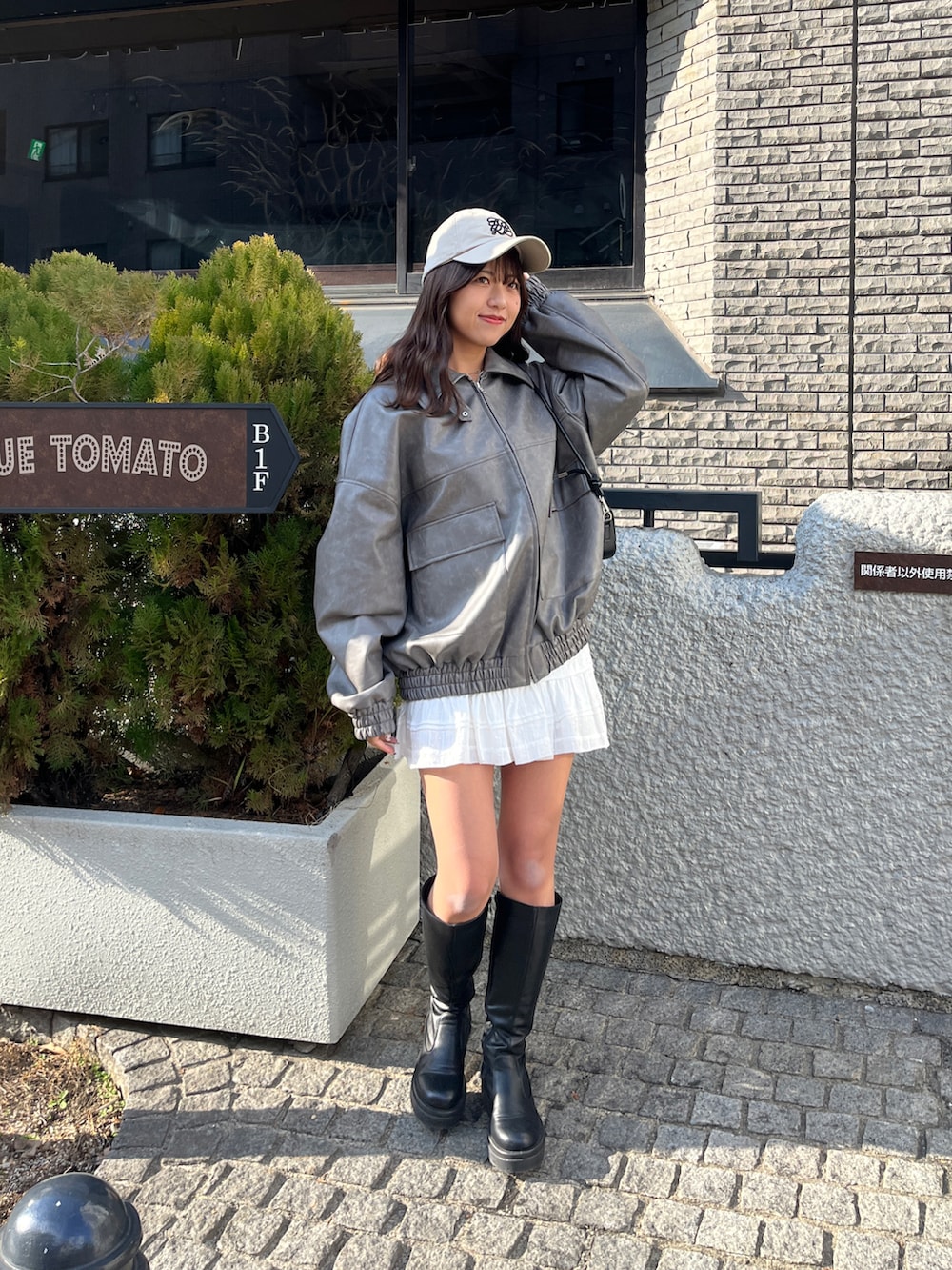 グレー系のライダースジャケット、ホワイト系のスカート、ベージュ系のキャップを着用したレディースの冬コーディネートの5枚目の写真