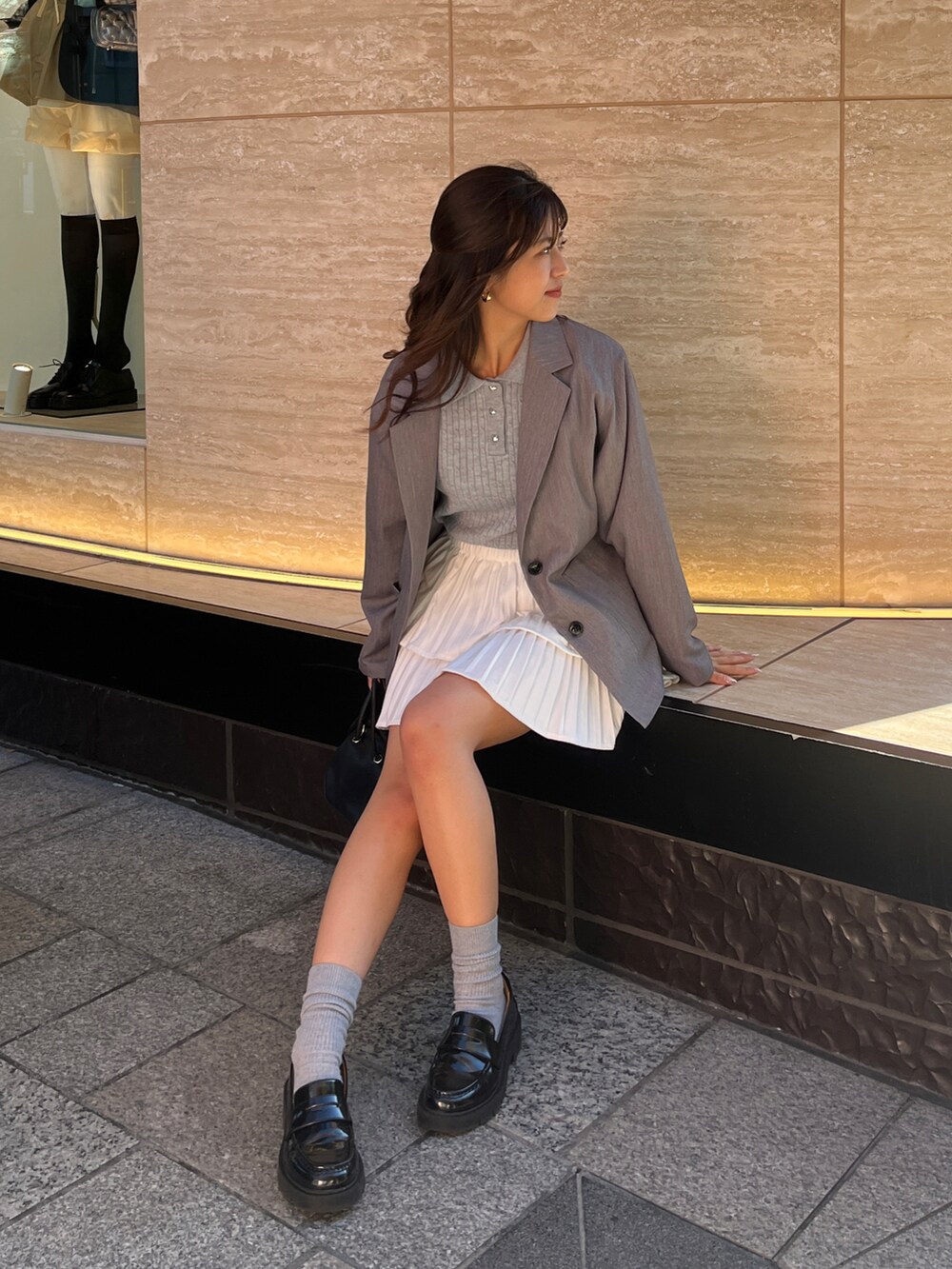 グレー系のテーラードジャケット、ブルー系のニット/セーター、ホワイト系のスカートを着用したレディースの冬コーディネートの4枚目の写真