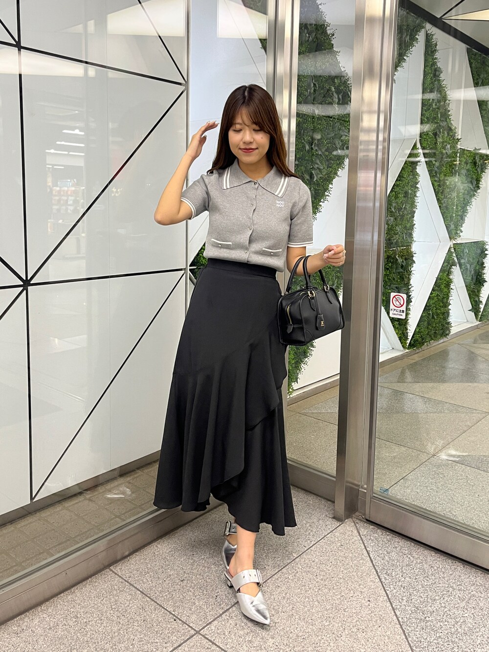 グレー系のワンピース、ブラック系のスカートを着用したレディースの春コーディネートの3枚目の写真