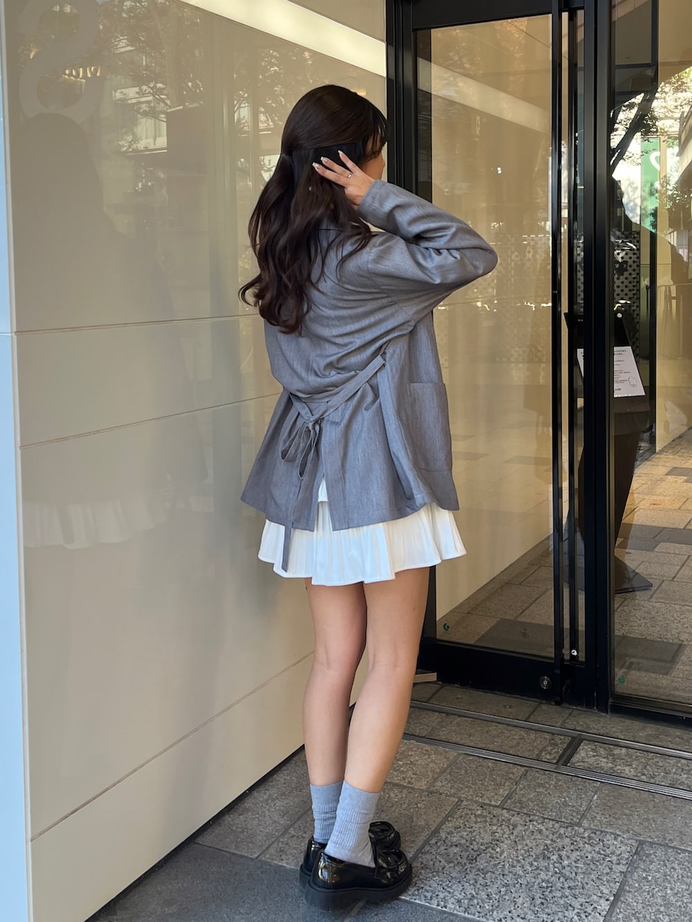 グレー系のテーラードジャケット、ブルー系のニット/セーター、ホワイト系のスカートを着用したレディースの冬コーディネートの3枚目の写真