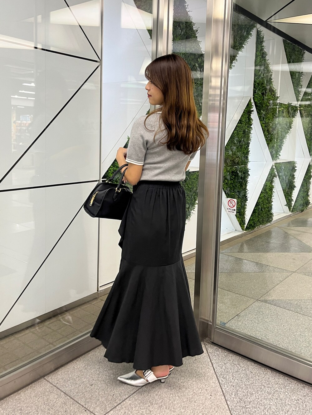 グレー系のワンピース、ブラック系のスカートを着用したレディースの春コーディネートの2枚目の写真