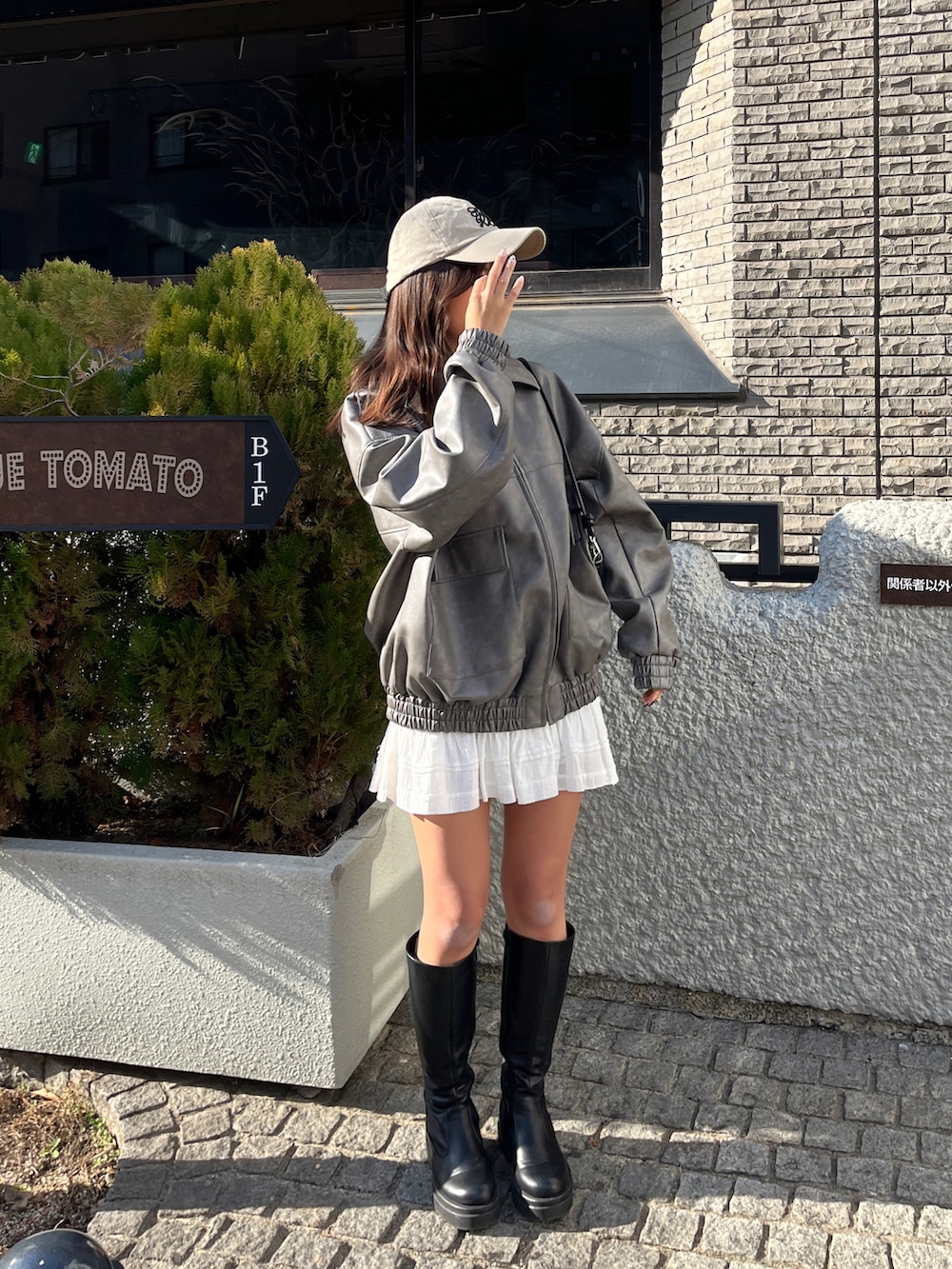 グレー系のライダースジャケット、ホワイト系のスカート、ベージュ系のキャップを着用したレディースの冬コーディネートの3枚目の写真