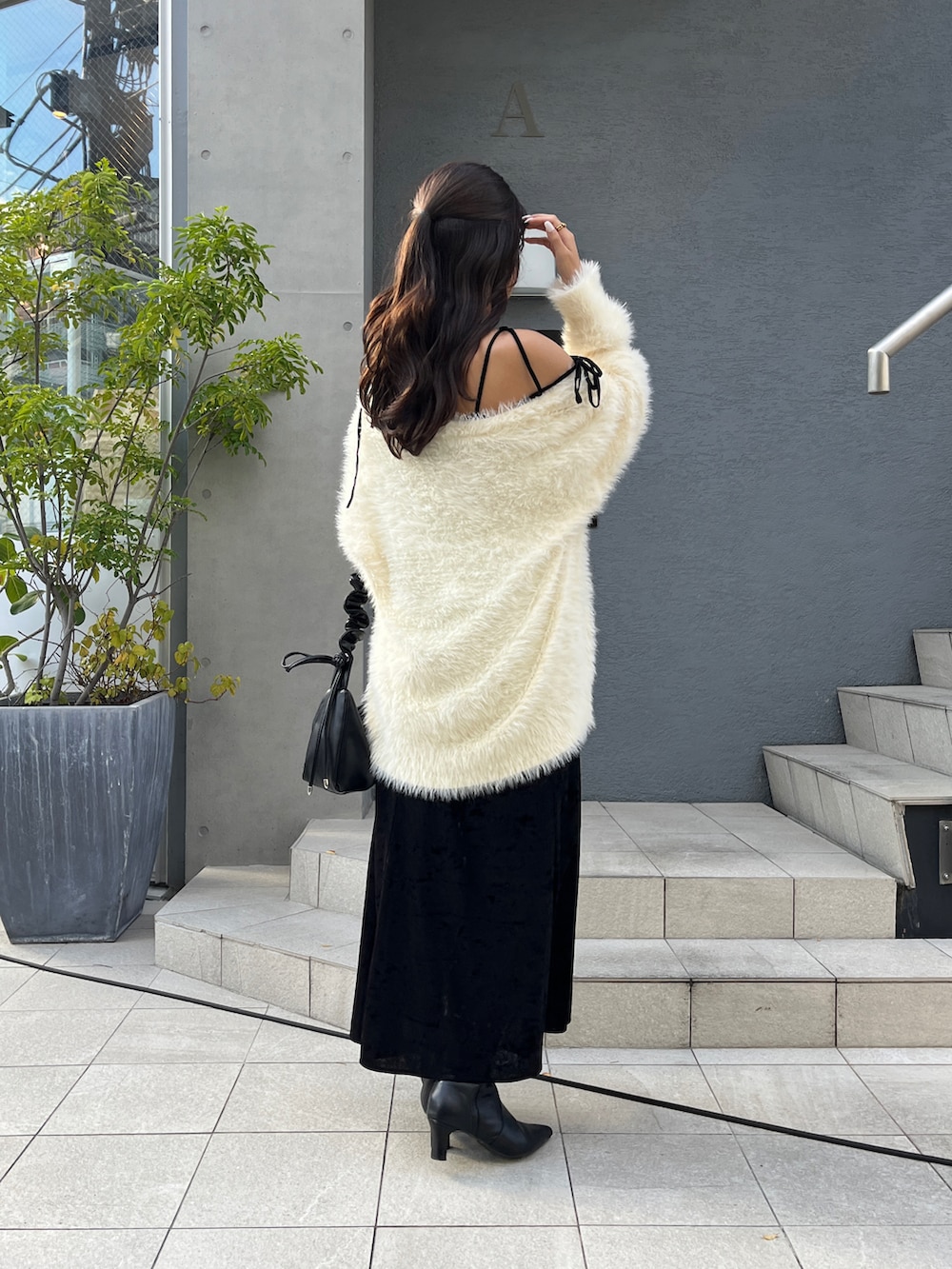 ホワイト系のカーディガン/ボレロ、ブラック系のワンピース、ブラック系のブーツを着用したレディースの秋コーディネートの2枚目の写真