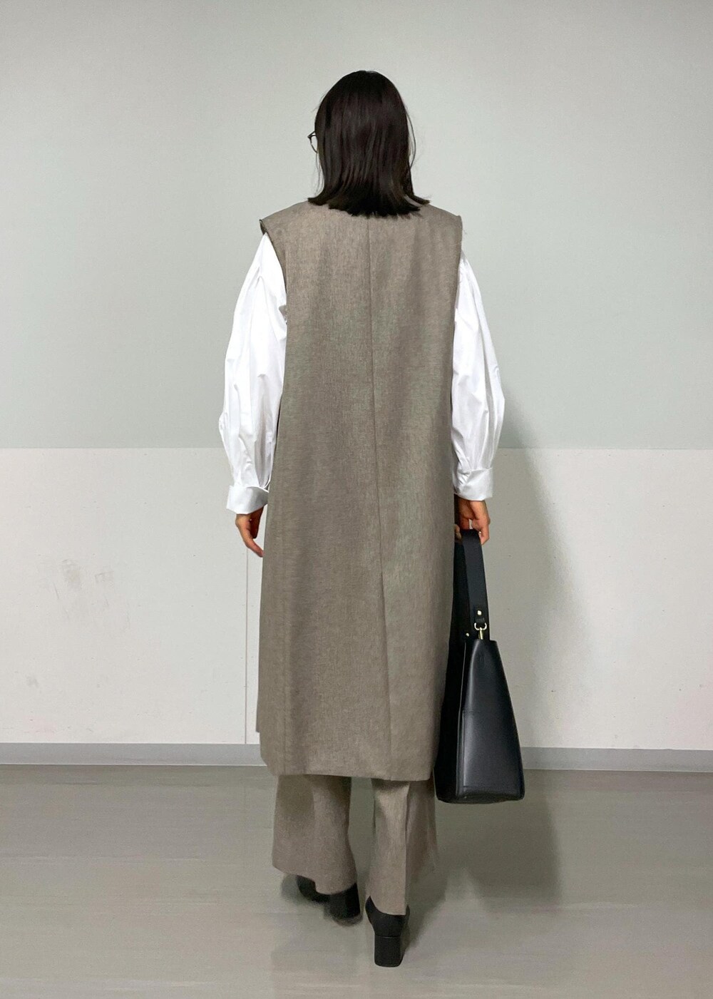 ベージュ系のスラックス、ベージュ系のジャンパースカート、ホワイト系のシャツ/ブラウスを着用したレディースの秋コーディネートの2枚目の写真