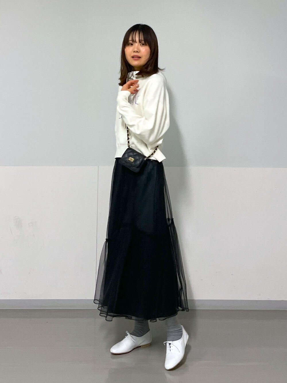 ブラック系のショルダーバッグ、ホワイト系のニット/セーター、ブラック系のスカートを着用したレディースの冬コーディネートの9枚目の写真