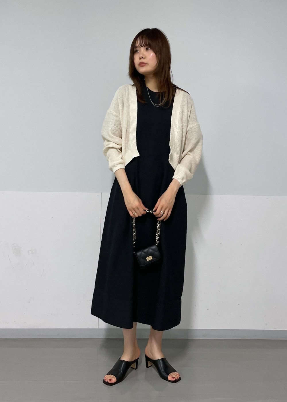 ブラック系のサンダル、ホワイト系のカーディガン/ボレロ、ブラック系のワンピースを着用したレディースの夏コーディネートの6枚目の写真