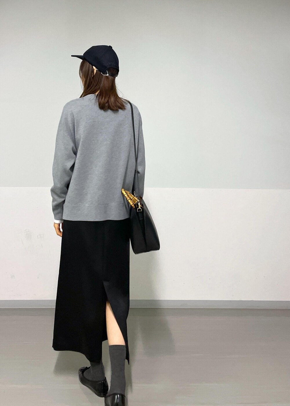 グレー系のカーディガン/ボレロ、ホワイト系のTシャツ/カットソー、ブラック系のハンドバッグを着用したレディースの冬コーディネートの2枚目の写真