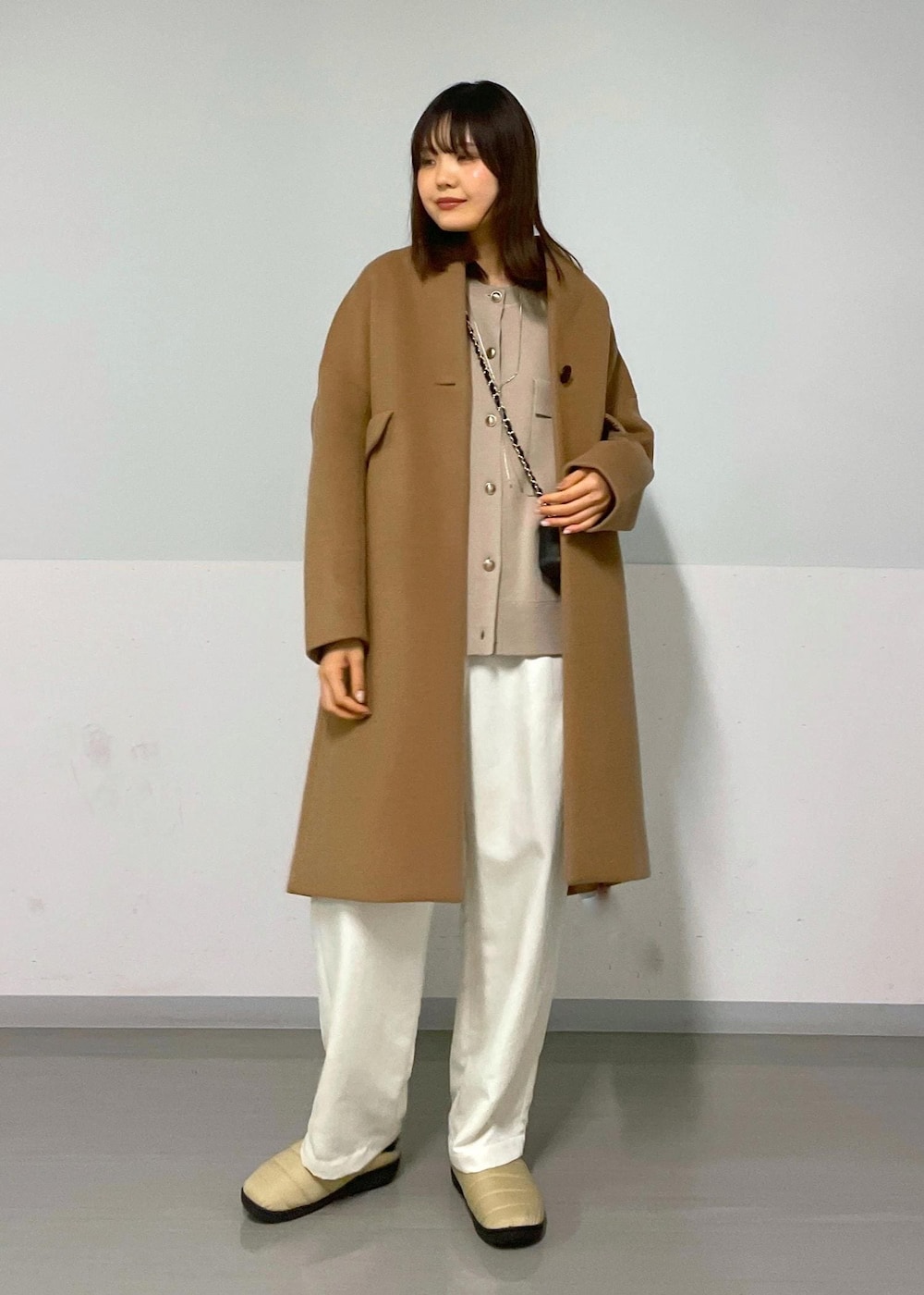 ブラック系のショルダーバッグ、イエロー系のチェスターコート、ベージュ系のカーディガン/ボレロを着用したレディースの冬コーディネートの2枚目の写真