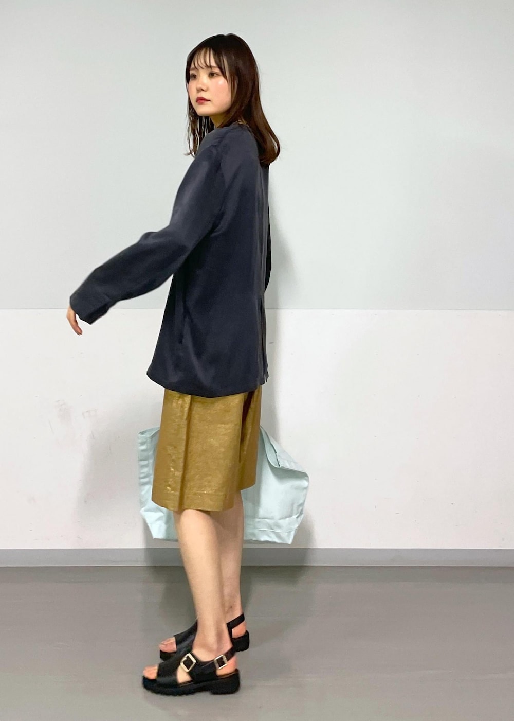 ゴールド系のその他パンツ、グレー系のノーカラージャケット、ブラック系のサンダルを着用したレディースの春コーディネートの6枚目の写真