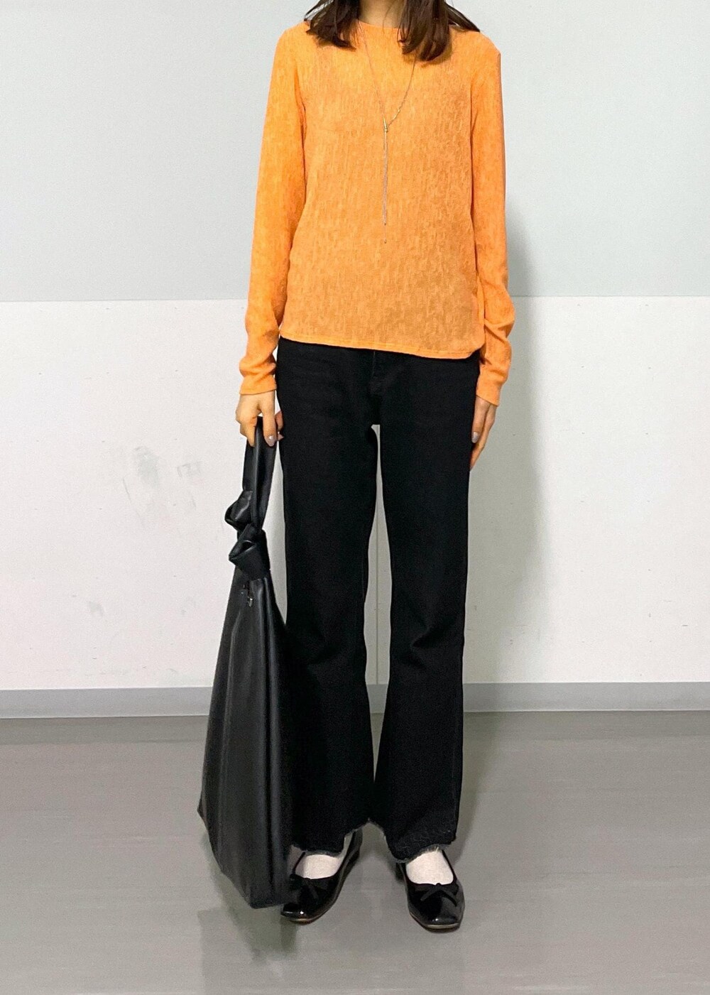 ブラック系のトートバッグ、グレー系のデニムパンツ、オレンジ系のTシャツ/カットソーを着用したレディースの冬コーディネートの10枚目の写真