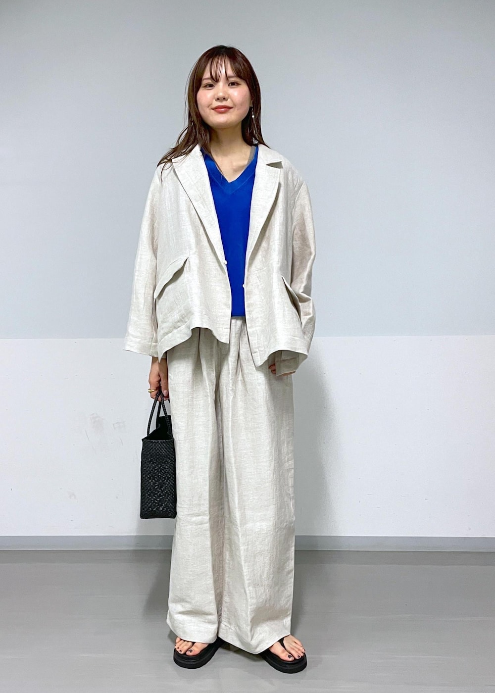 ブラック系のかごバッグ、ホワイト系のスラックス、ホワイト系のテーラードジャケットを着用したレディースの春コーディネートの2枚目の写真