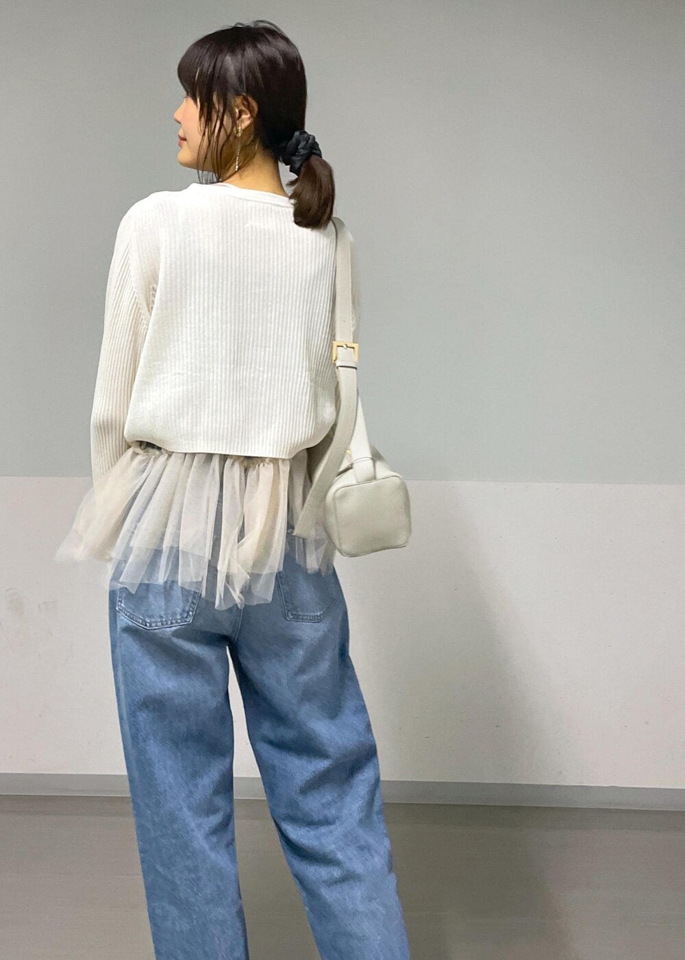 ブラック系のバレエシューズ、ホワイト系のカーディガン/ボレロ、ブルー系のデニムパンツを着用したレディースの秋コーディネートの2枚目の写真