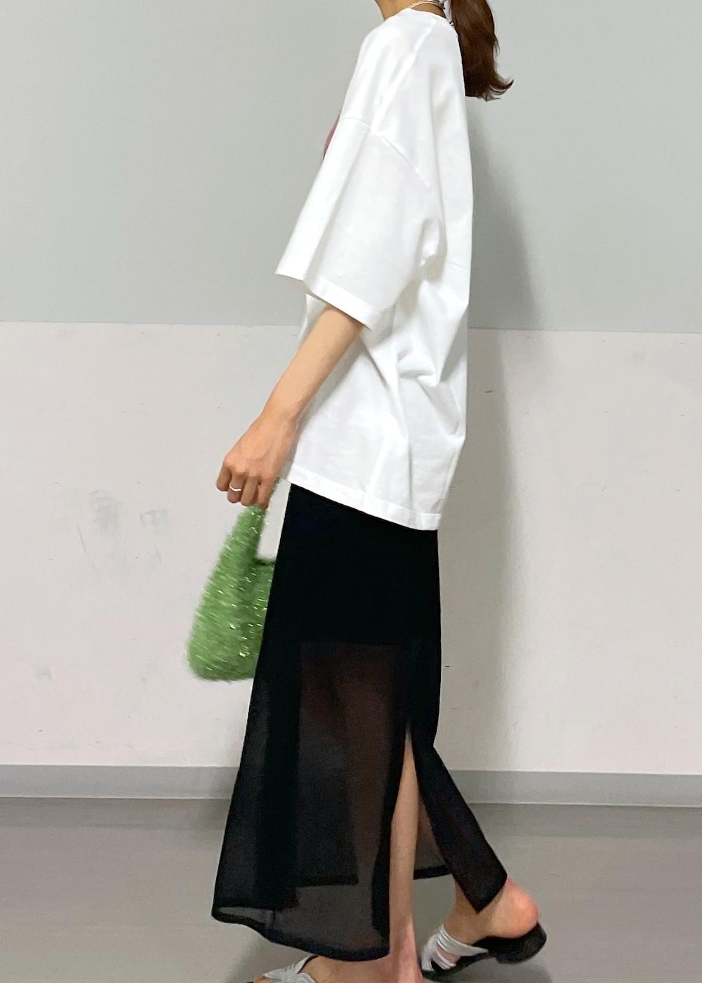 ブラック系のスカート、グリーン系のハンドバッグ、ホワイト系のTシャツ/カットソーを着用したレディースの夏コーディネートの7枚目の写真