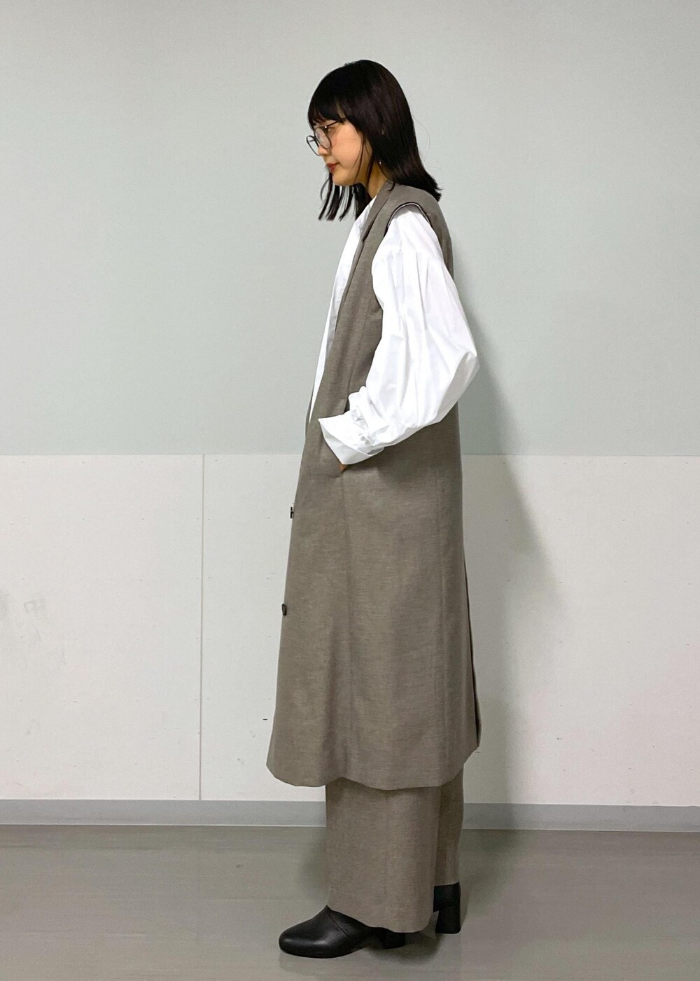 ベージュ系のスラックス、ベージュ系のジャンパースカート、ホワイト系のシャツ/ブラウスを着用したレディースの秋コーディネートの3枚目の写真