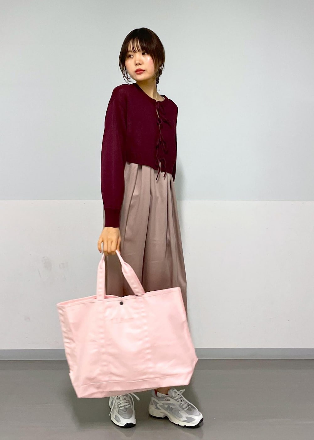 レッド系のニット/セーター、イエロー系のワンピース、ホワイト系のスニーカーを着用したレディースの春コーディネートの2枚目の写真