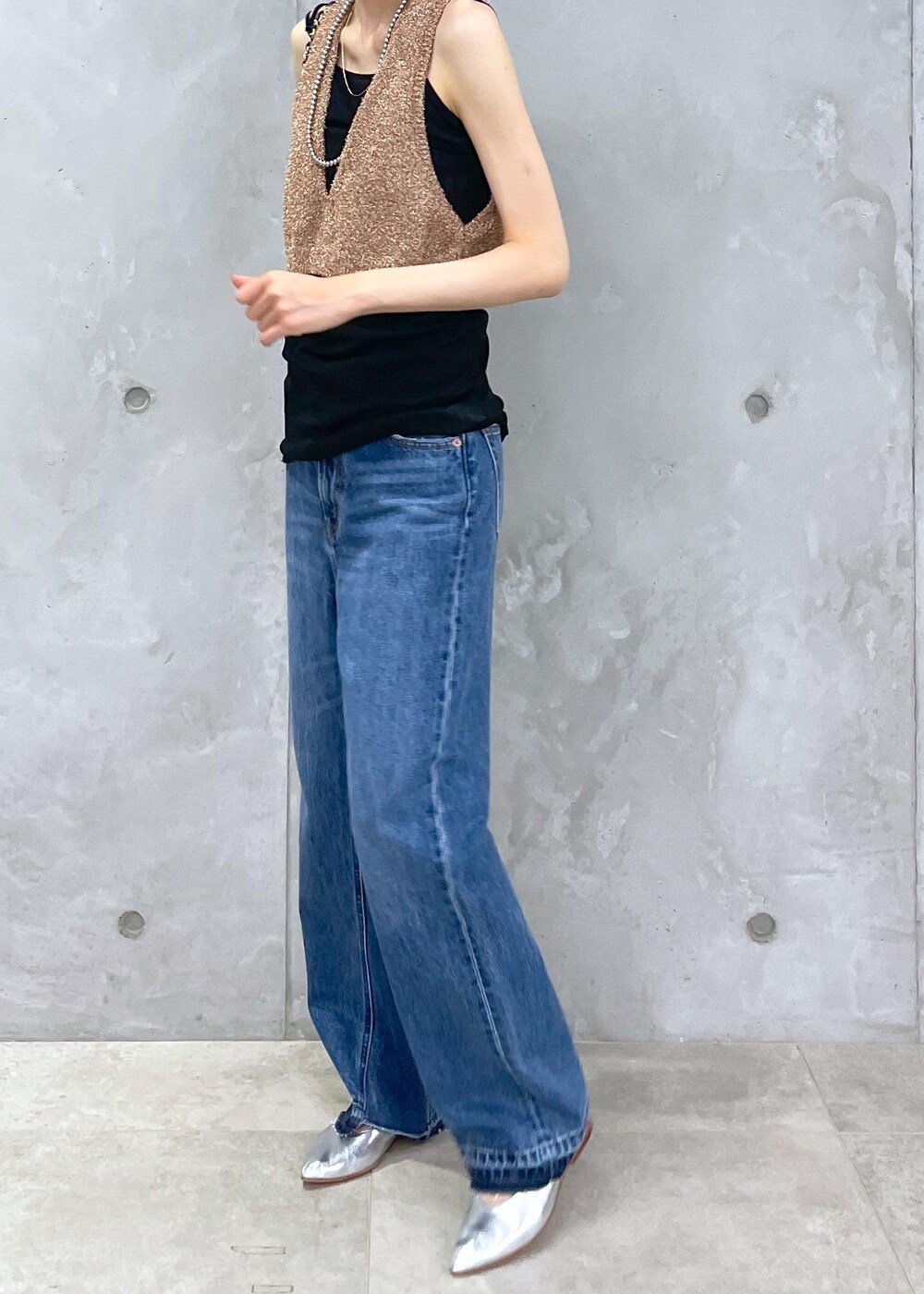 ブラック系のショルダーバッグ、ブルー系のデニムパンツ、ゴールド系のベストを着用したレディースの春コーディネートの10枚目の写真