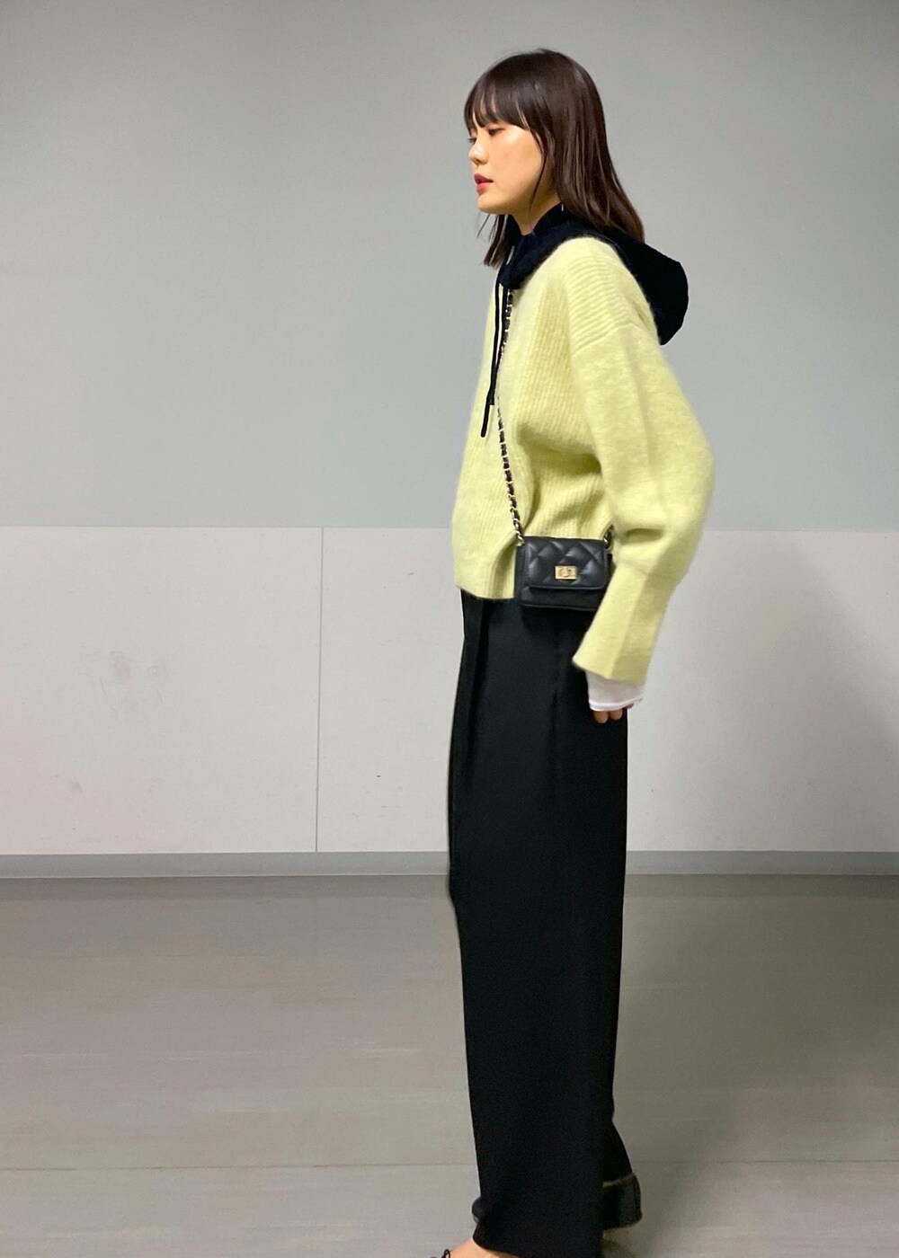 ブラック系のショルダーバッグ、イエロー系のニット/セーター、ホワイト系のTシャツ/カットソーを着用したレディースの秋コーディネートの2枚目の写真