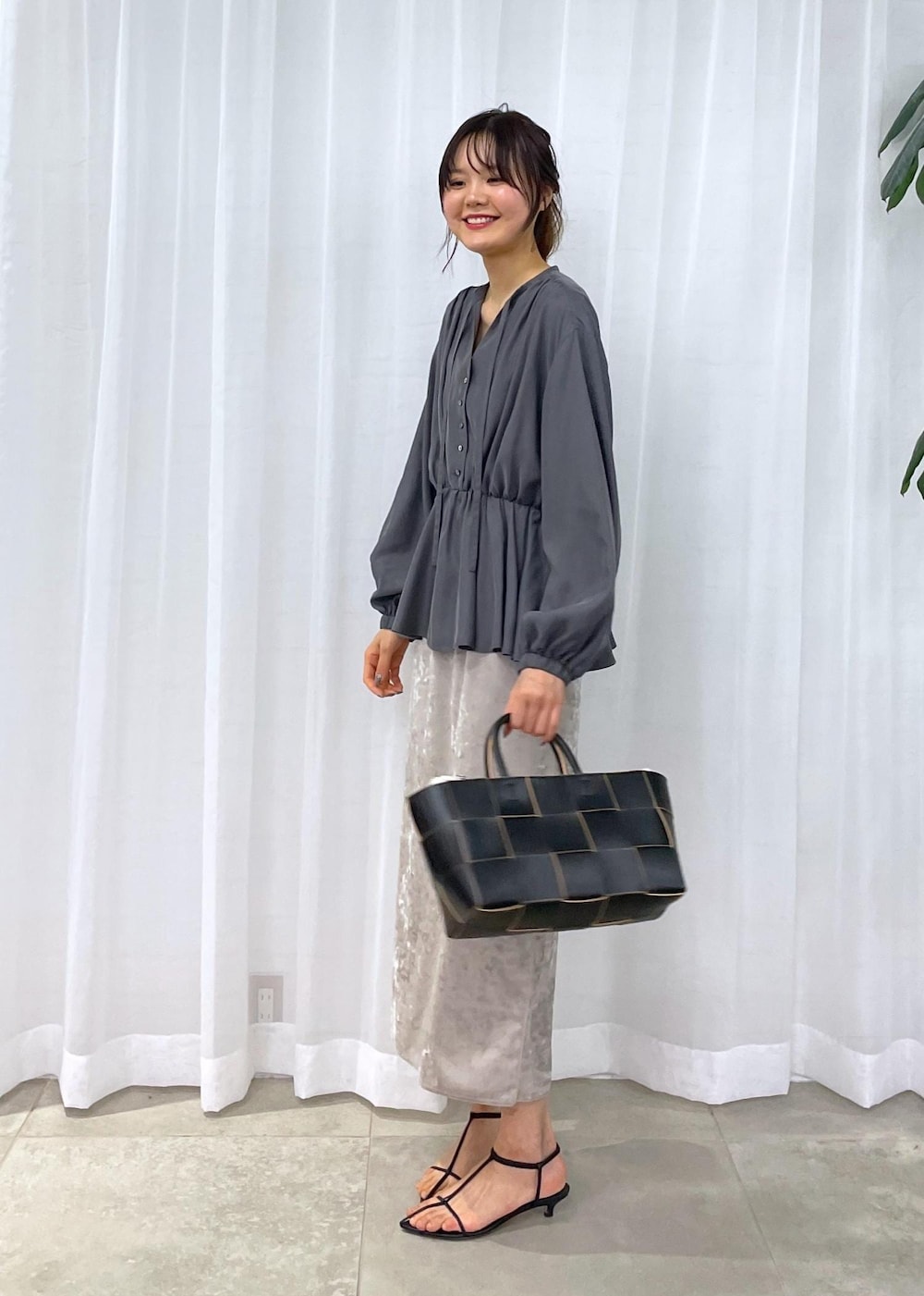 ブラック系のトートバッグ、ベージュ系のスカート、グレー系のシャツ/ブラウスを着用したレディースの冬コーディネートの2枚目の写真