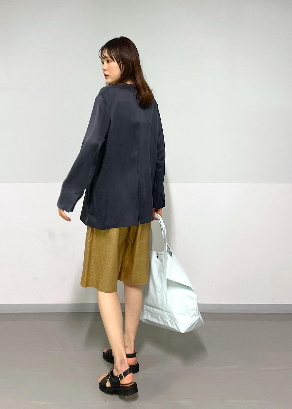 ゴールド系のその他パンツ、グレー系のノーカラージャケット、ブラック系のサンダルを着用したレディースの春コーディネートの9枚目の写真