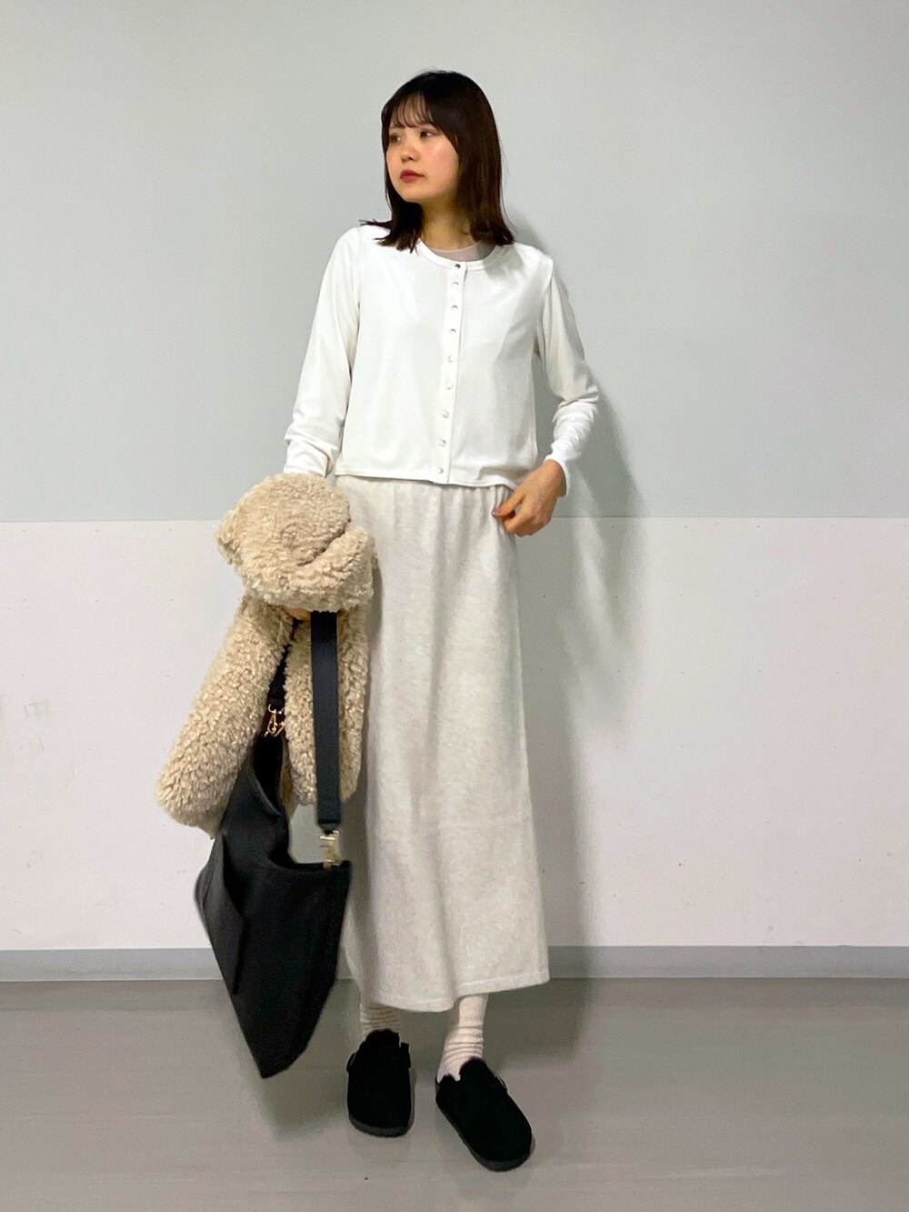 ホワイト系のカーディガン/ボレロ、ベージュ系のベスト、ホワイト系のスカートを着用したレディースの冬コーディネートの4枚目の写真