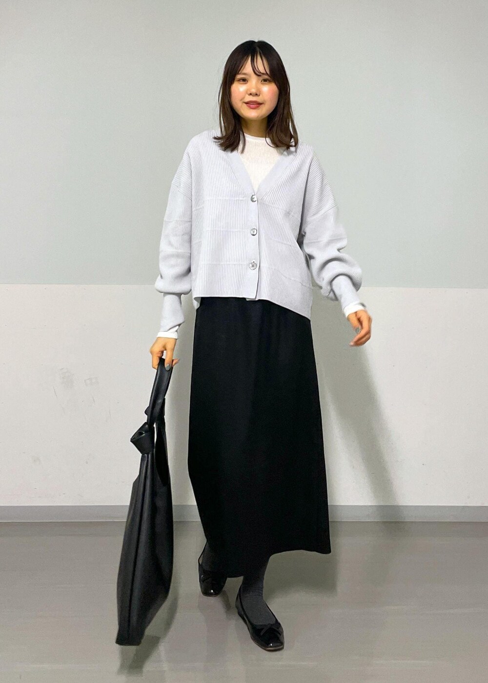 ブラック系のトートバッグ、ホワイト系のTシャツ/カットソー、グレー系のカーディガン/ボレロを着用したレディースの冬コーディネートの9枚目の写真