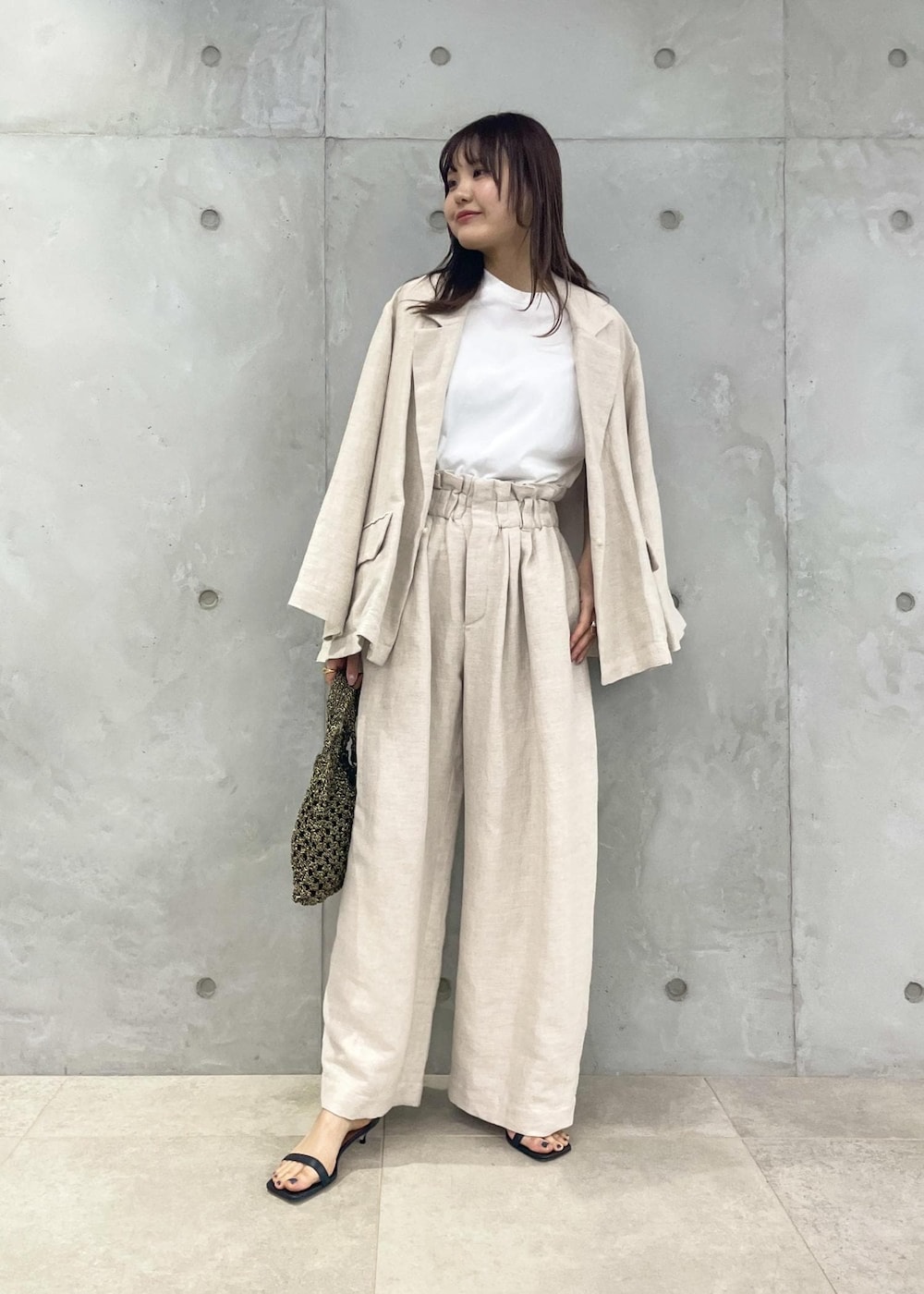 ブラック系のサンダル、ホワイト系のスラックス、ホワイト系のテーラードジャケットを着用したレディースの春コーディネートの2枚目の写真
