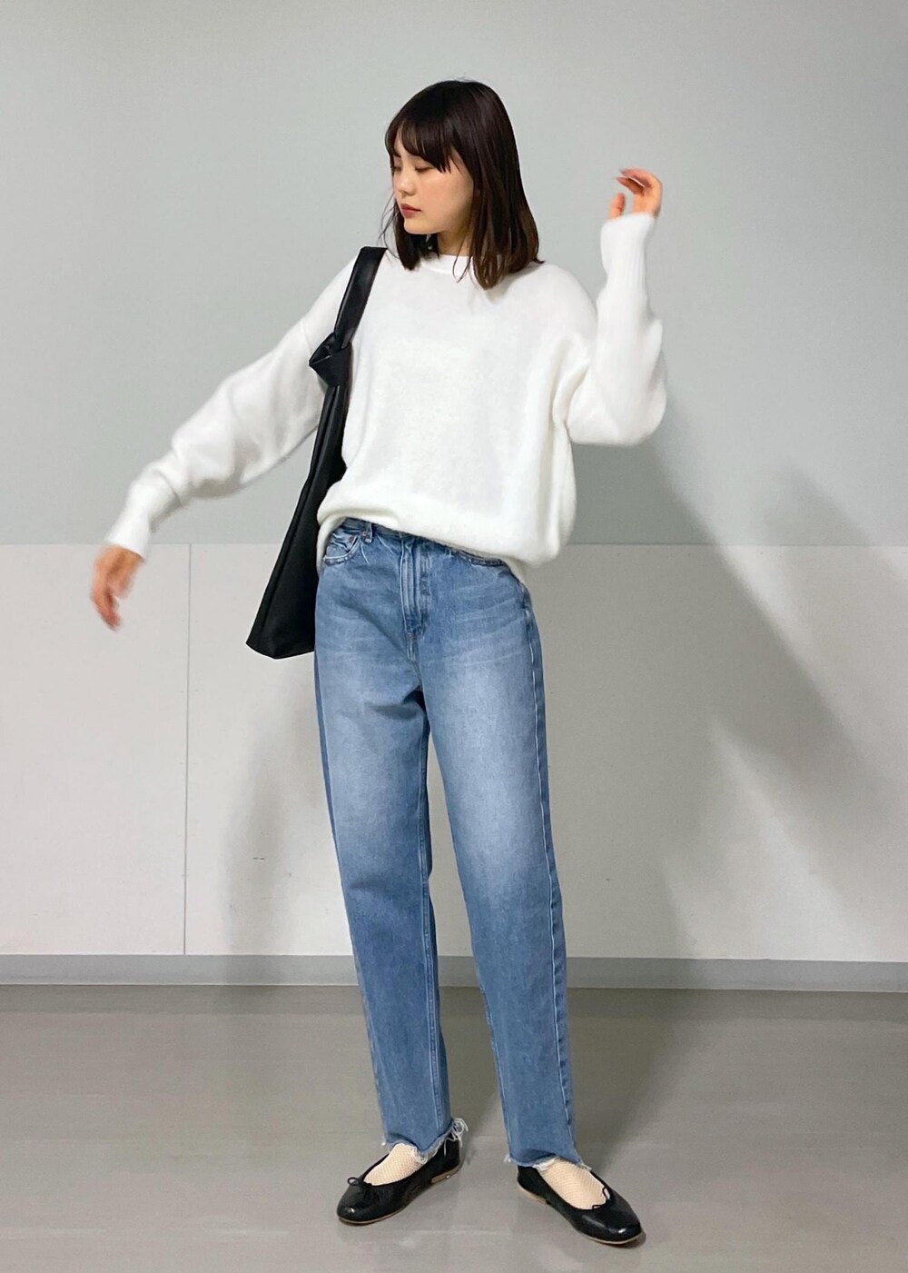 ブラック系のバレエシューズ、ブルー系のデニムパンツ、ホワイト系のニット/セーターを着用したレディースの秋コーディネートの2枚目の写真