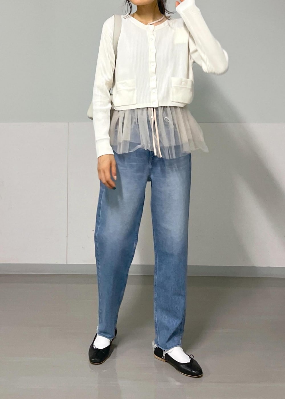ブラック系のバレエシューズ、ホワイト系のカーディガン/ボレロ、ブルー系のデニムパンツを着用したレディースの秋コーディネートの4枚目の写真
