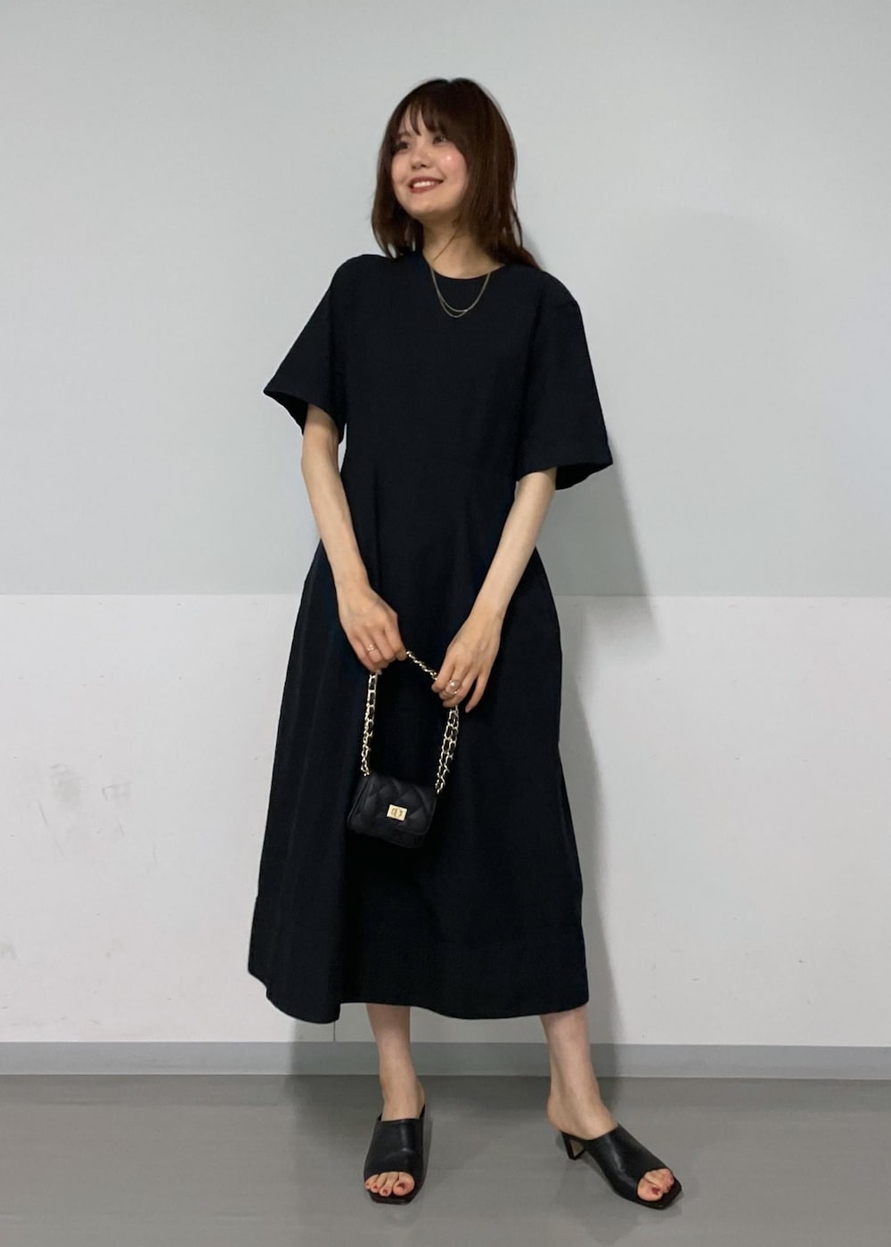 ブラック系のサンダル、ホワイト系のカーディガン/ボレロ、ブラック系のワンピースを着用したレディースの夏コーディネートの2枚目の写真