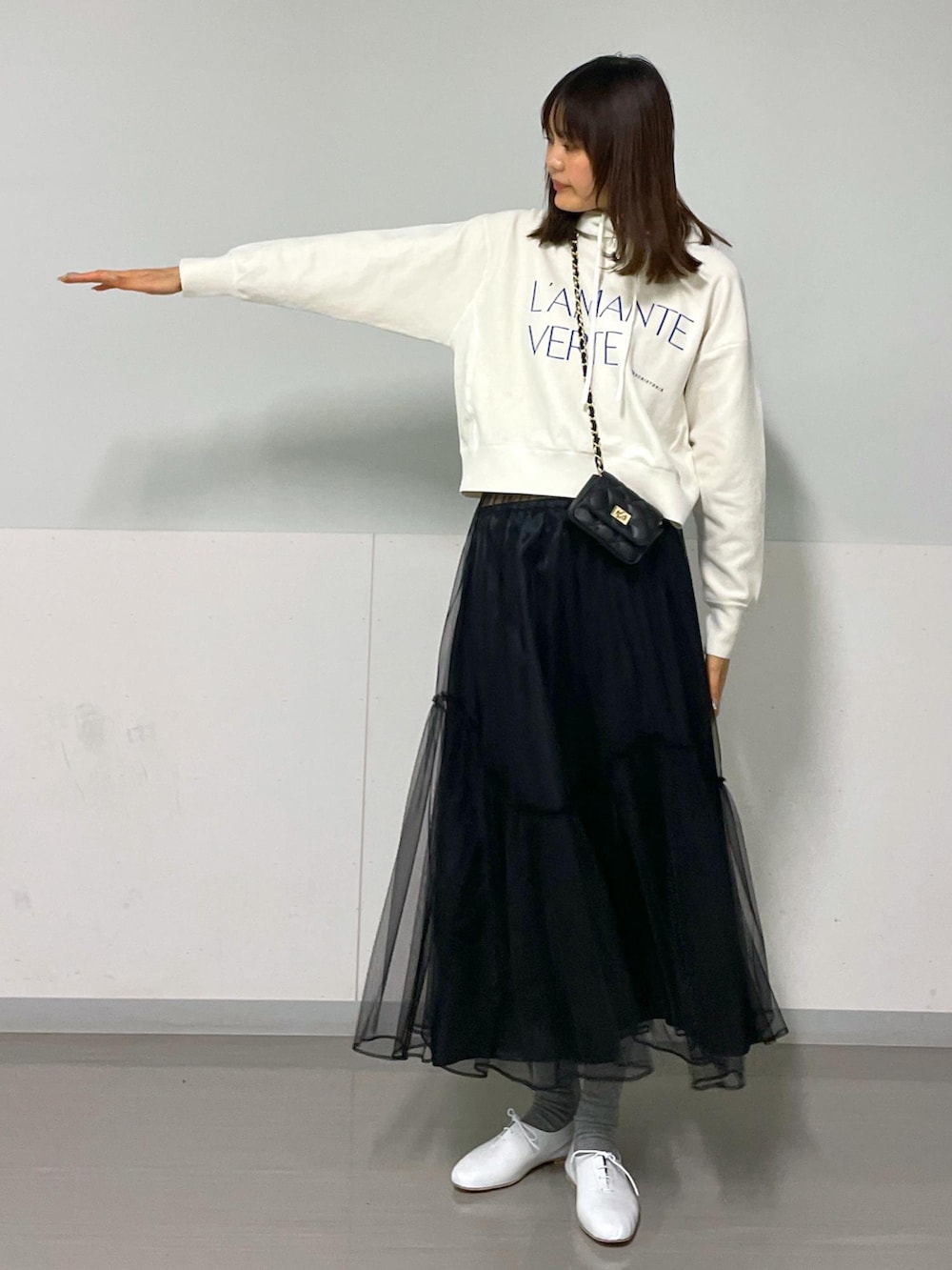 ブラック系のショルダーバッグ、ホワイト系のニット/セーター、ブラック系のスカートを着用したレディースの冬コーディネートの4枚目の写真