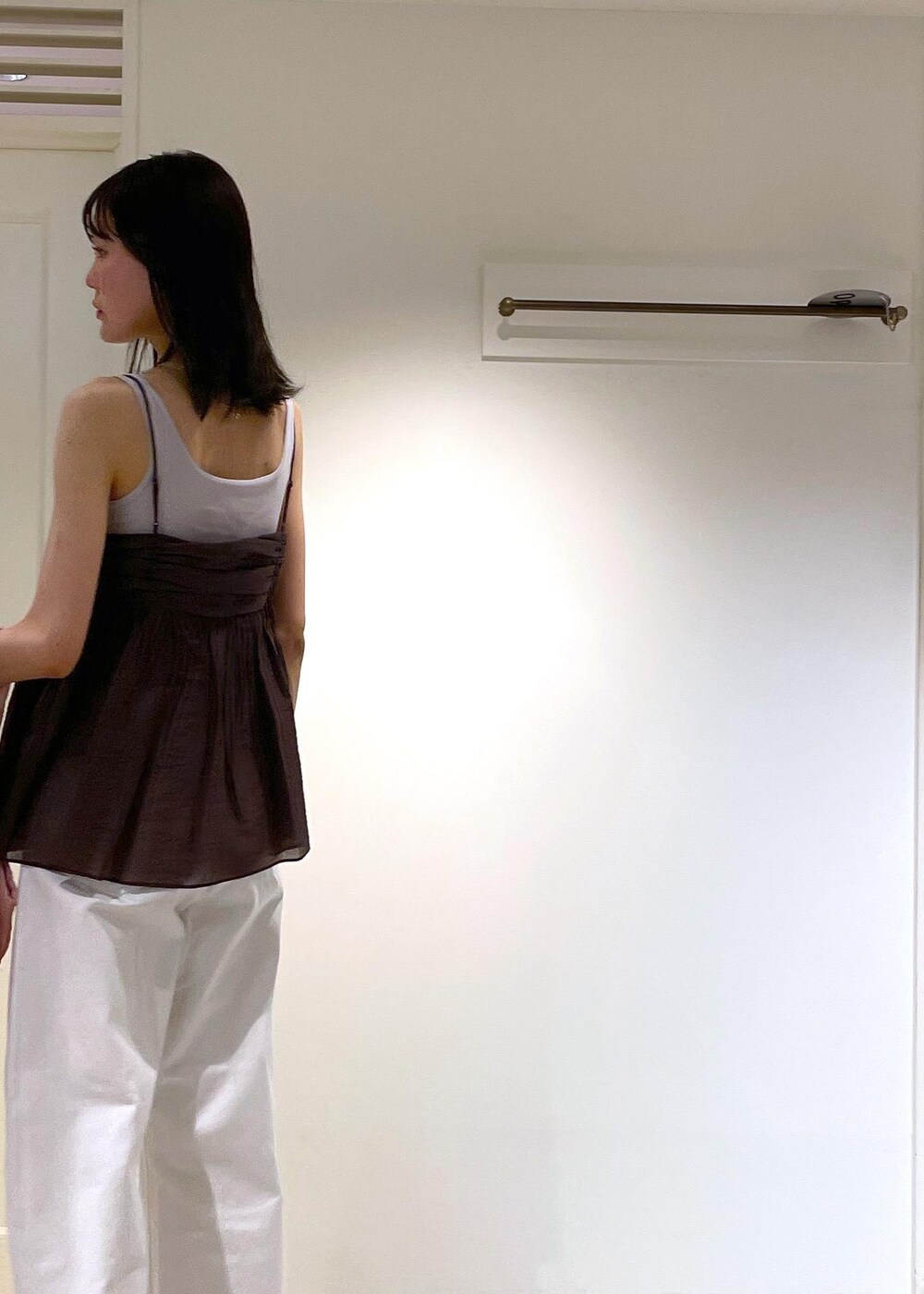 グレー系のタンクトップ、ブラック系のサンダル、ホワイト系のデニムパンツを着用したレディースの夏コーディネートの9枚目の写真