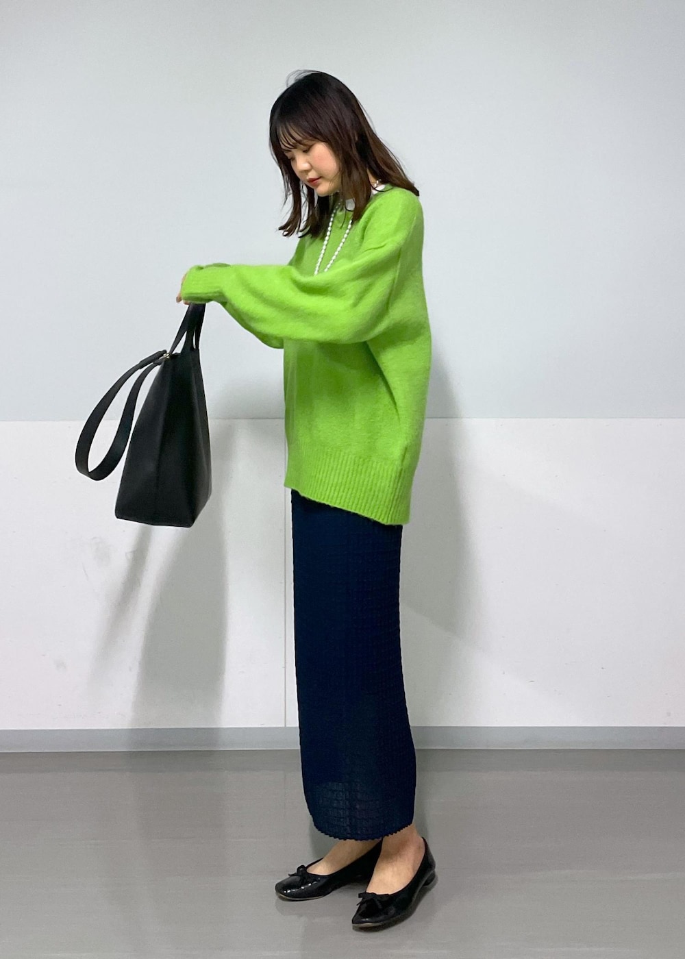 グリーン系のニット/セーター、ホワイト系のTシャツ/カットソー、ブラック系のトートバッグを着用したレディースの冬コーディネートの3枚目の写真