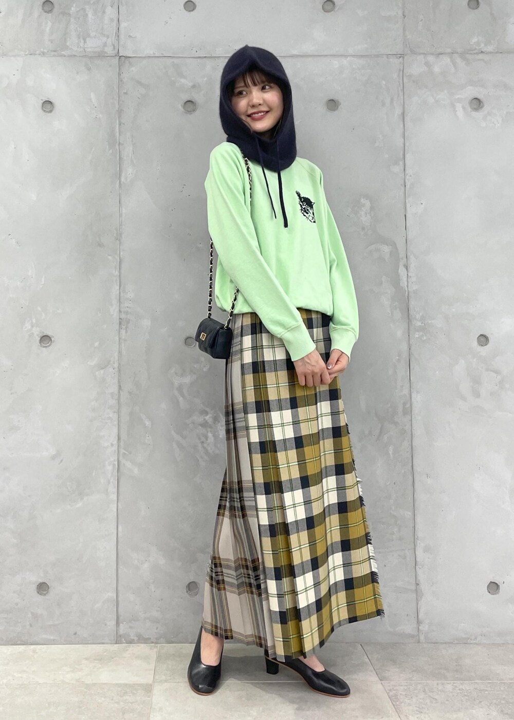 イエロー系のスカート、グリーン系のスウェット、ブラック系のショルダーバッグを着用したレディースの夏コーディネートの4枚目の写真