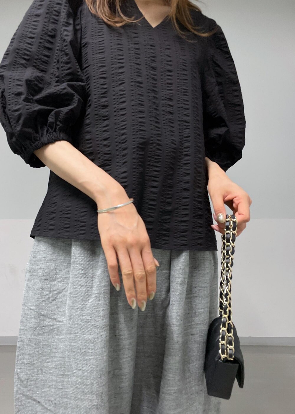 ブラック系のショルダーバッグ、グレー系のスラックス、ブラック系のシャツ/ブラウスを着用したレディースの夏コーディネートの6枚目の写真