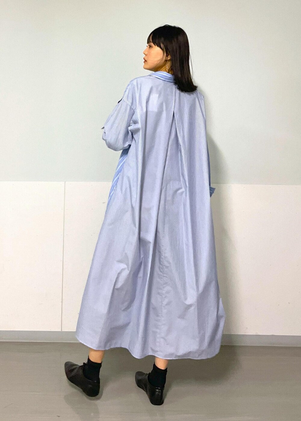 ブラック系のショルダーバッグ、ブルー系のシャツワンピース、ホワイト系のネックレスを着用したレディースの秋コーディネートの10枚目の写真