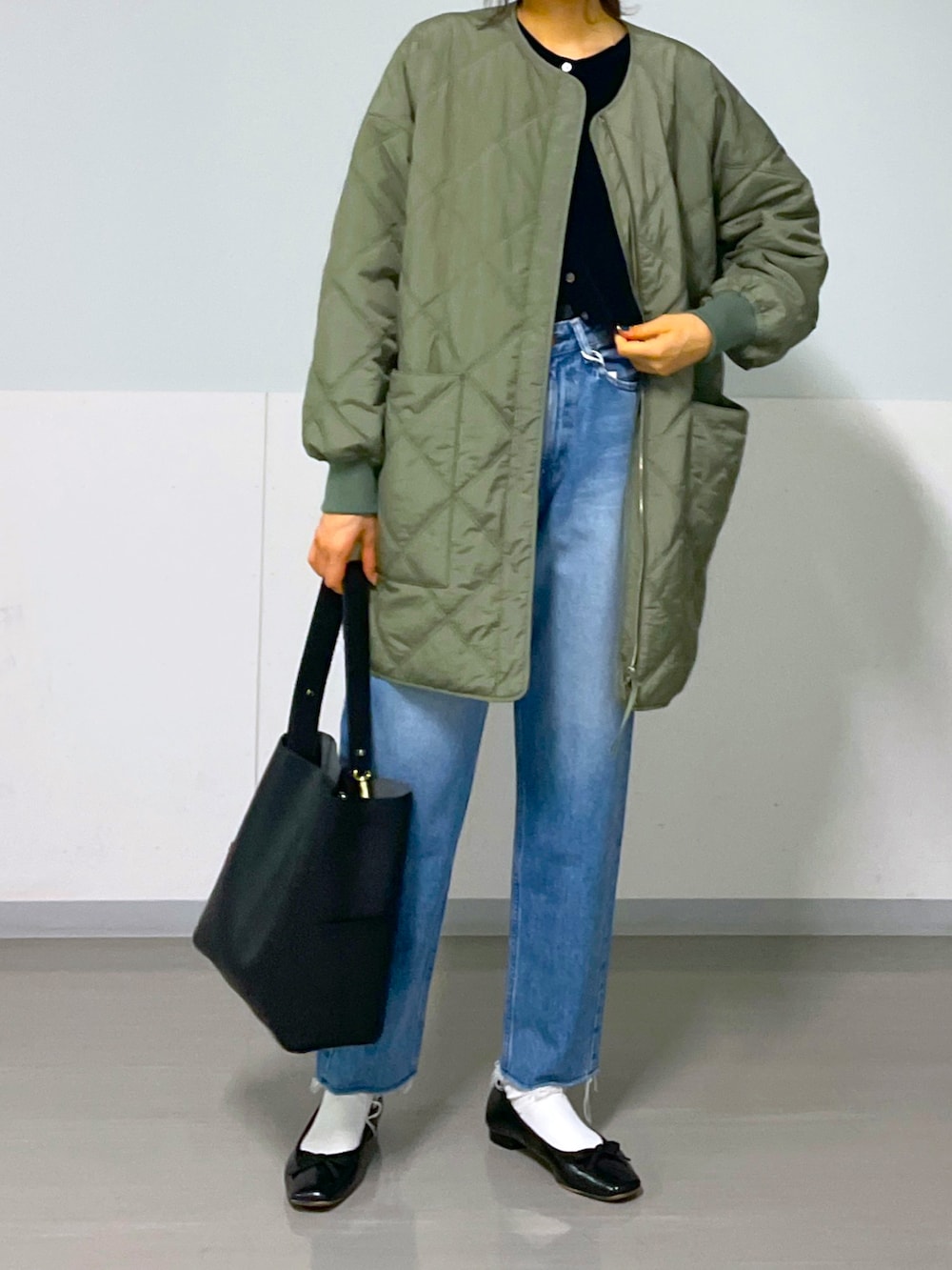 グリーン系のブルゾン、ブルー系のデニムパンツ、ブラック系のバレエシューズを着用したレディースの秋コーディネートの5枚目の写真