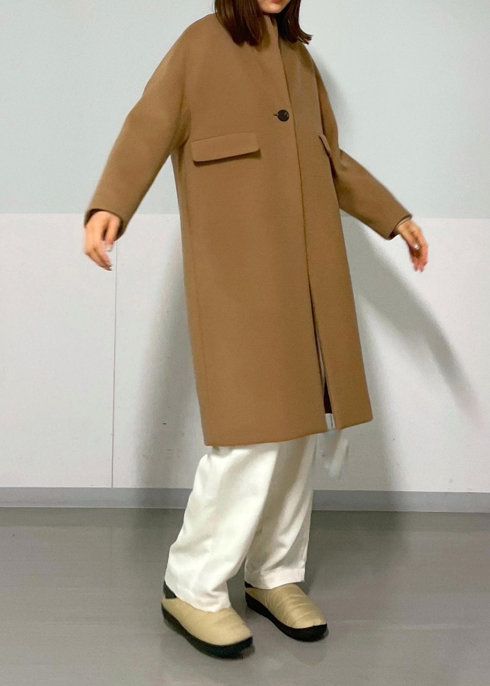 ブラック系のショルダーバッグ、イエロー系のチェスターコート、ベージュ系のカーディガン/ボレロを着用したレディースの冬コーディネートの7枚目の写真