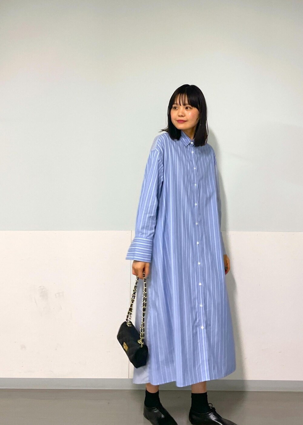 ブラック系のショルダーバッグ、ブルー系のシャツワンピース、ホワイト系のネックレスを着用したレディースの秋コーディネートの6枚目の写真