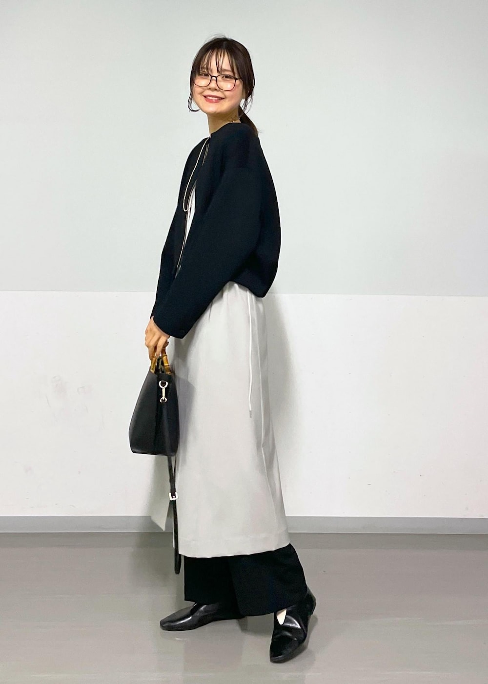 ベージュ系のジャンパースカート、ブラック系のブルゾン、ブラック系のスラックスを着用したレディースの春コーディネートの2枚目の写真