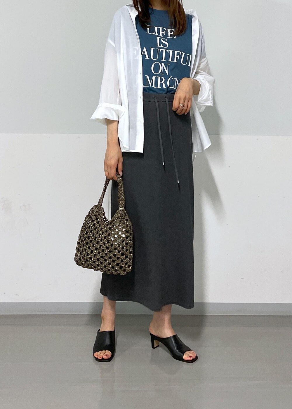 ブルー系のTシャツ/カットソー、ブラック系のハンドバッグ、グレー系のスカートを着用したレディースの夏コーディネートの5枚目の写真