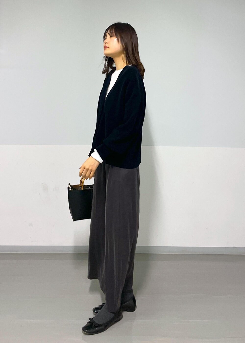 グレー系のスカート、ブラック系のカーディガン/ボレロ、ホワイト系のTシャツ/カットソーを着用したレディースの冬コーディネートの6枚目の写真