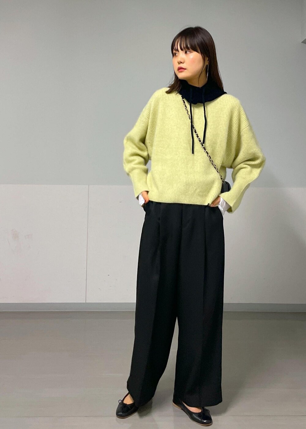 ブラック系のショルダーバッグ、イエロー系のニット/セーター、ホワイト系のTシャツ/カットソーを着用したレディースの秋コーディネートの3枚目の写真