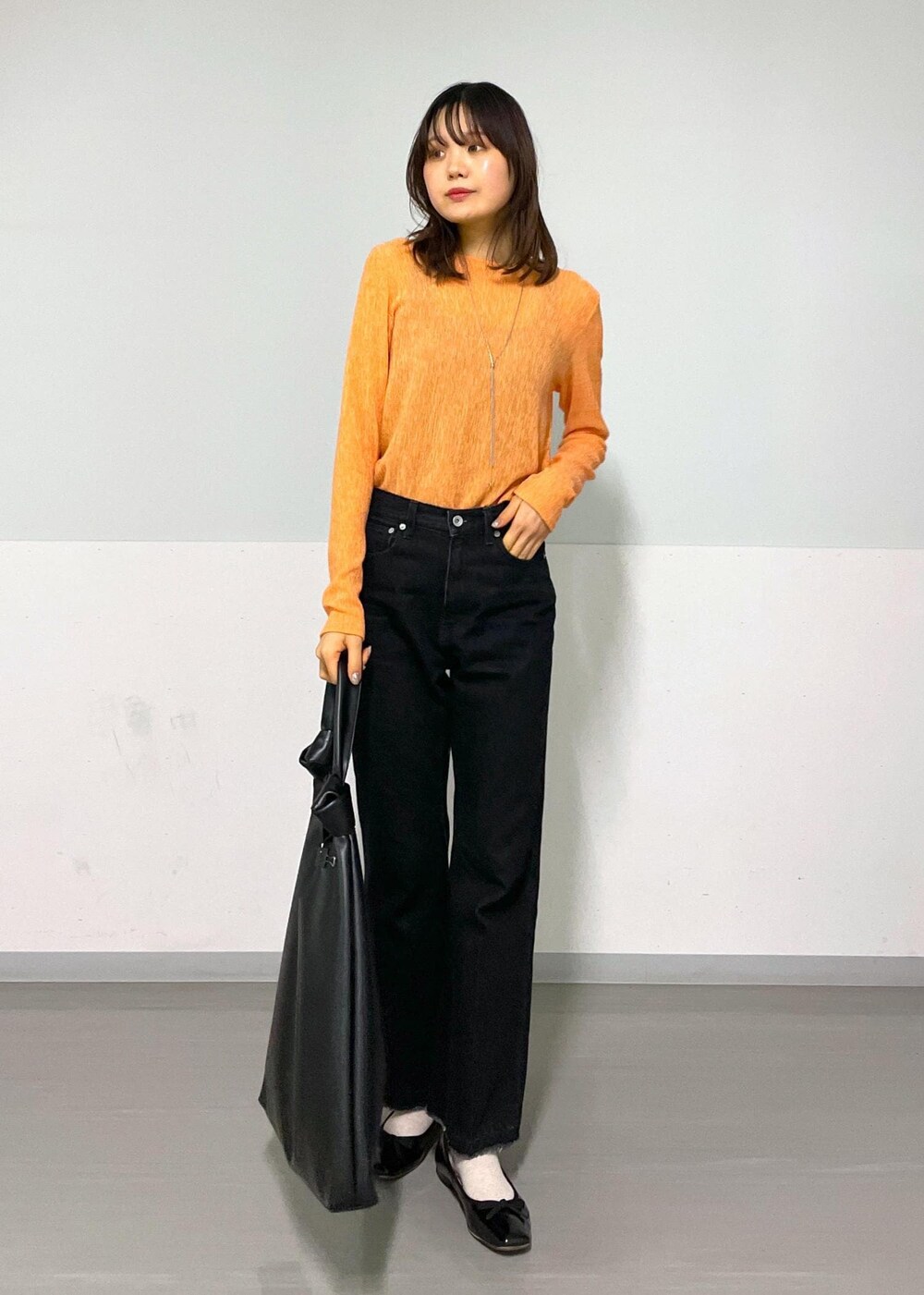 ブラック系のトートバッグ、グレー系のデニムパンツ、オレンジ系のTシャツ/カットソーを着用したレディースの冬コーディネートの9枚目の写真